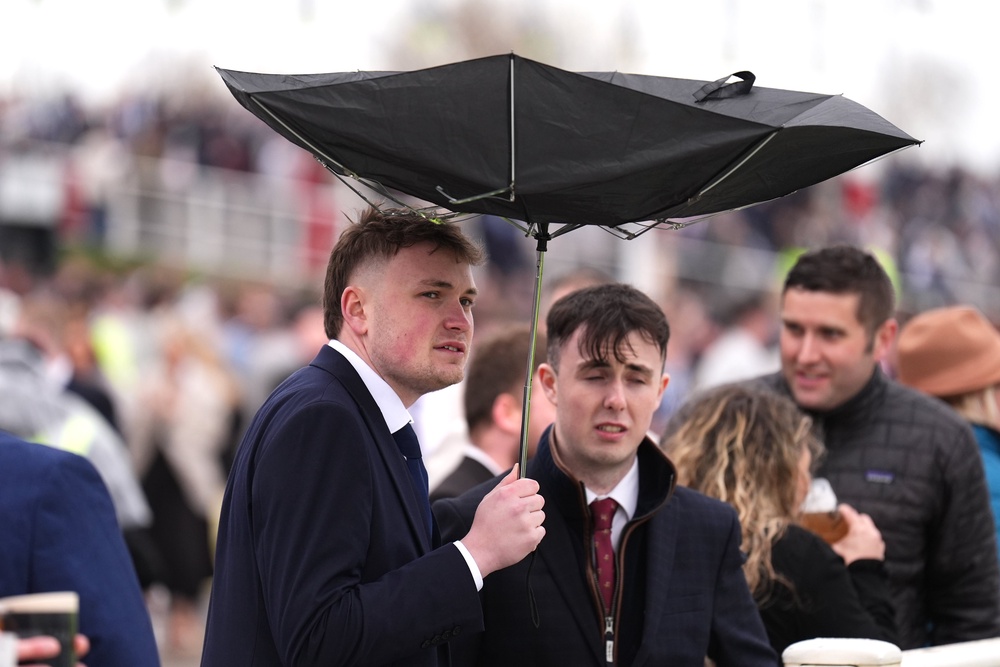 A racegoer holds an umbrella which is inside out on Grand National Day of the Randox Grand National Festival 2026 at Aintree Racecourse (Mike Egerton/PA) (PA Wire)