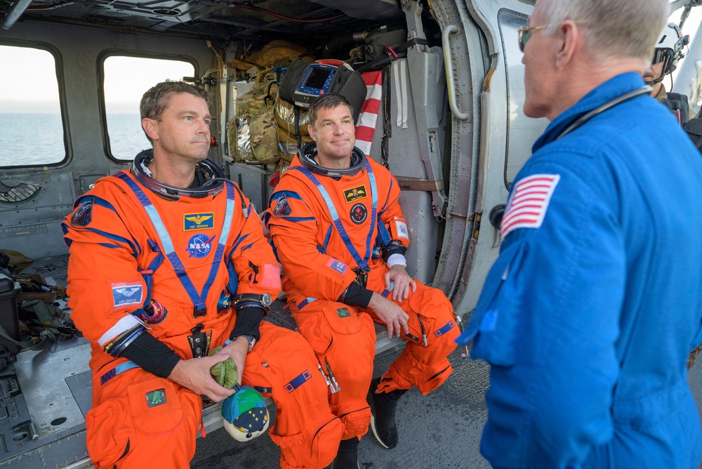 Artemis II commander Reid Wiseman (of NASA) and mission specialist Jeremy Hansen (of the Canadian Space Agency talk with NASA Flight Surgeon Richard Scheuring after being airlifted from their crew capsule by a U.S. Navy MH-60 Seahawk (Bill Ingalls/NASA/AFP Photo via Getty Images)