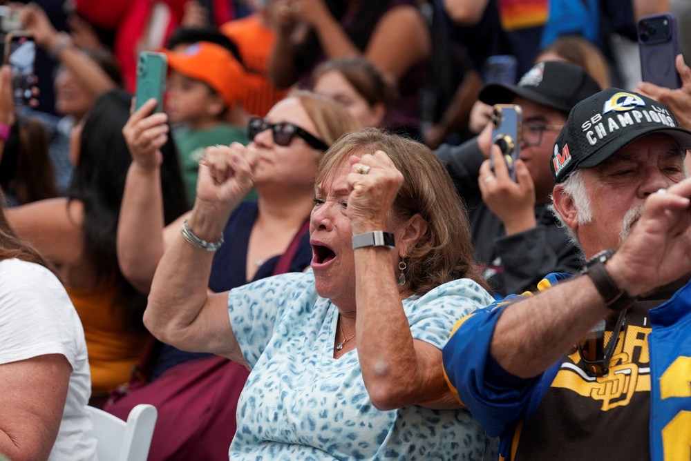 A woman raises her fists in triumph as she watches the Artemis II Orion capsule splash down off the coast of San Diego at the Air and Space Museum in San Diego, California, U.S., April 10, 2026. (REUTERS/Arafat Barbakh)