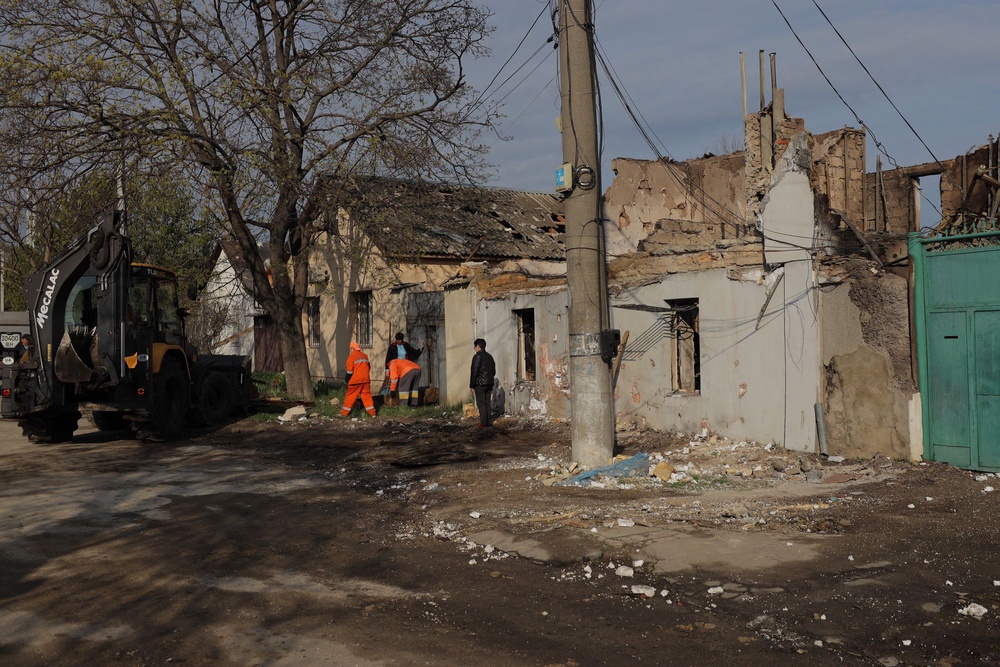Communal workers clean debris next to a destroyed house following an air attack in Odesa (AFP via Getty Images)