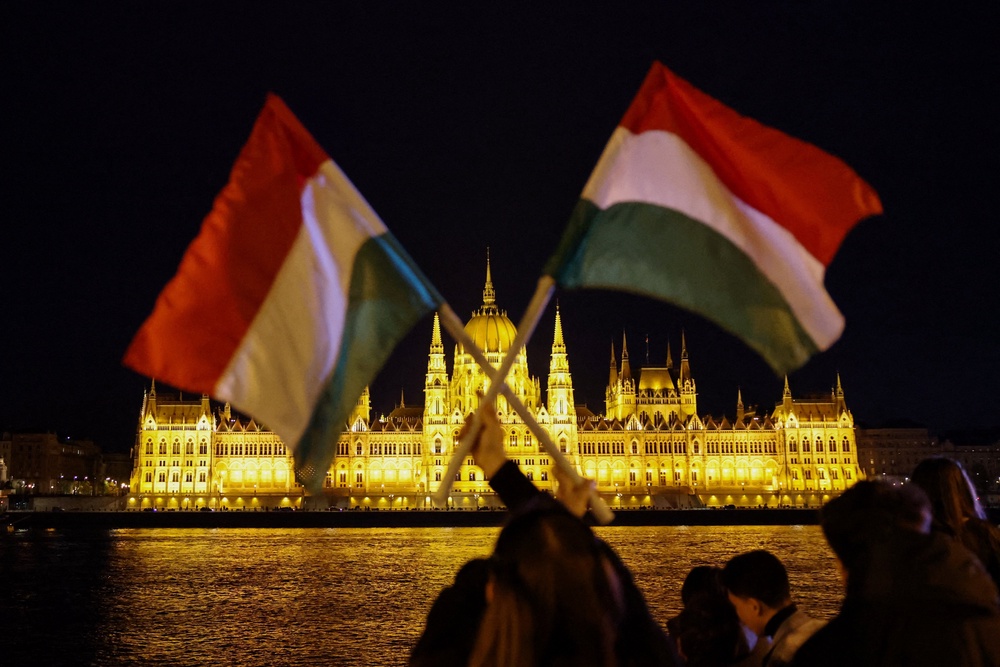 A person holds up Hungarian flags, across the River Danube from the Parliament building (REUTERS)