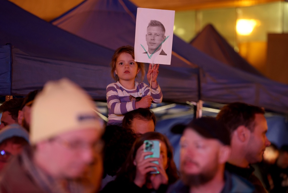 A child holds a picture of opposition candidate Peter Magyar with a green check mark among people gathered at a local outdoor post-election watch party following the closing of polling stations in Hungarian parliamentary elections (Getty Images)
