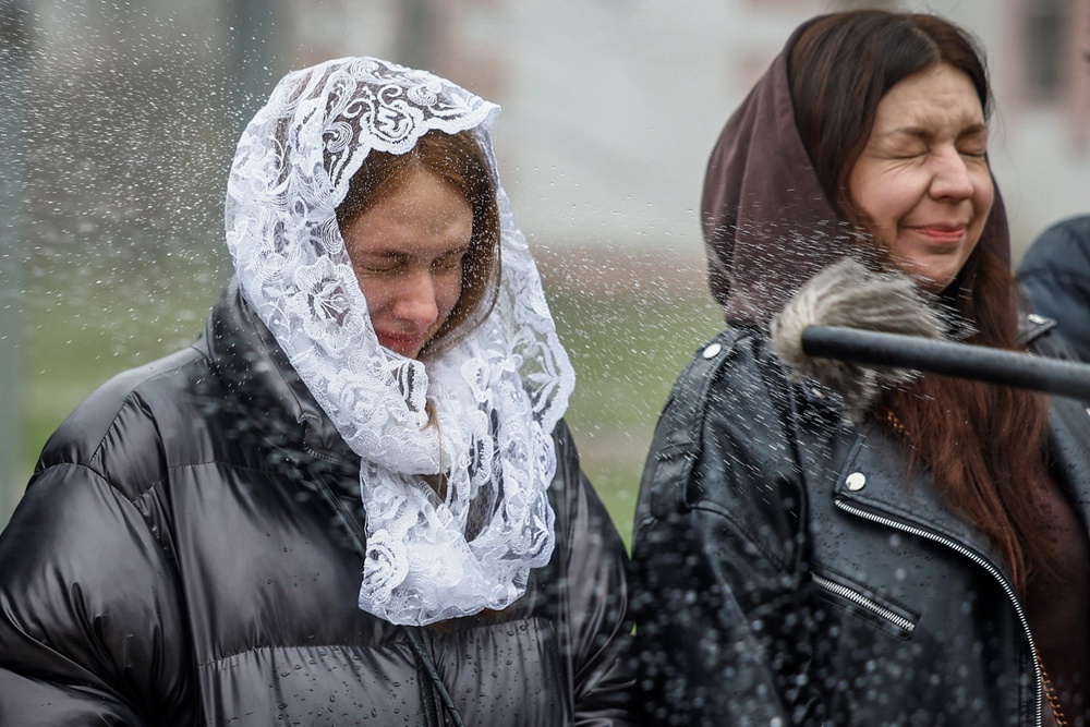 Orthodox Christians react as a priest blesses them with holy water during an Easter service in Bucha (REUTERS)