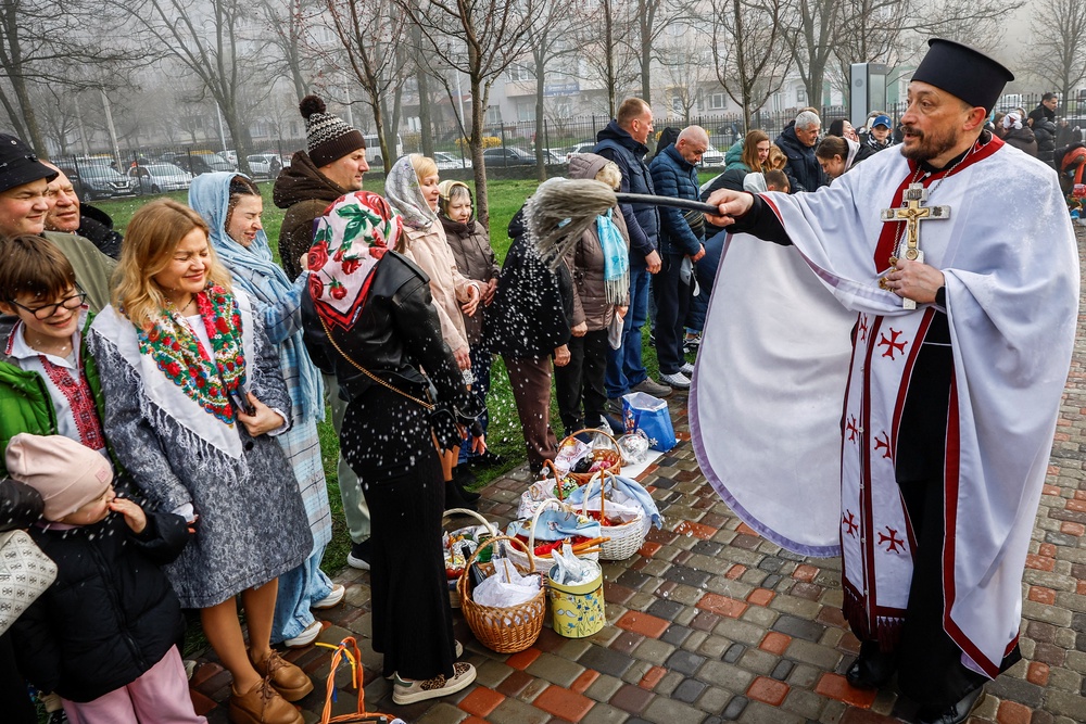 Believers react as a priest blesses by sprinkling holy water during an Orthodox Easter service near St Andrew's Church in the town of Bucha (REUTERS)