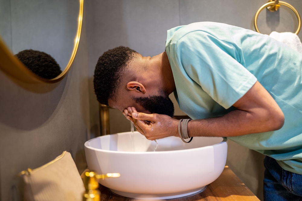 Man washing his face with water in a bathroom sink (Alamy/PA) (Alamy/PA)
