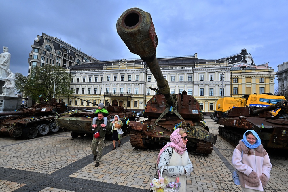 Local residents carry their baskets loaded with traditional cakes and eggs as they walk past an open-air exhibition of destroyed Russian military equipment during Easter celebrations in Kyiv (AFP/Getty)