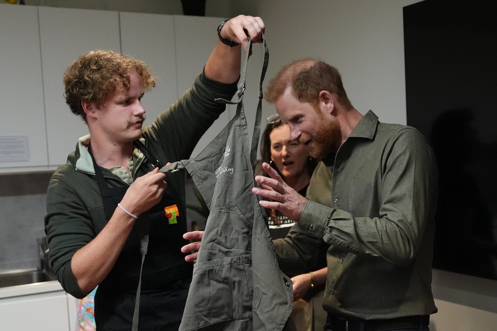 The Duke of Sussex puts on an apron as he takes part in a model making activity with veterans (Jonathan Brady/PA) (PA Wire)