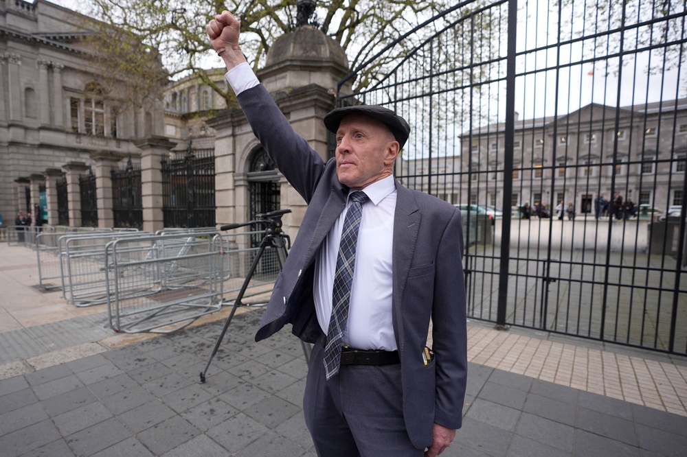 Independent TD Michael Healy-Rae waves to the crowds gathered outside Leinster House after resigning in the Dail as minister of state (Niall Carson/PA Wire)