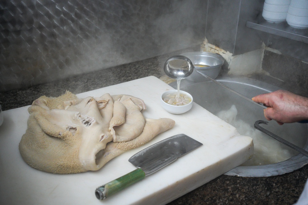 A man puts the finishing touches to the traditional tripe soup in Istanbul (AP)