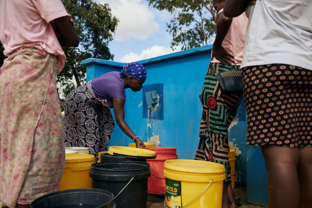 Miriam Nyirenda, middle, collects water from a water kiosk in Sylvia Masebo Community, Lusaka, Zambia (Lee-Ann Olwage/WaterAid)