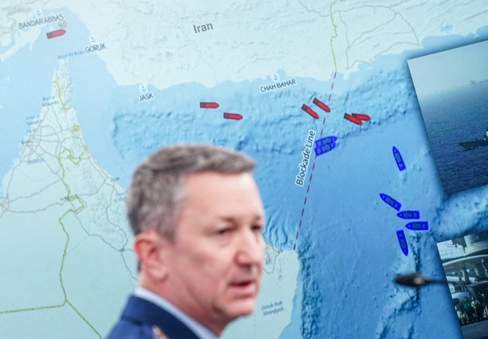 General Dan Caine speaks during a briefing on the Iran war, with a map in the background showing a blockade line on the Strait of Hormuz (Reuters)