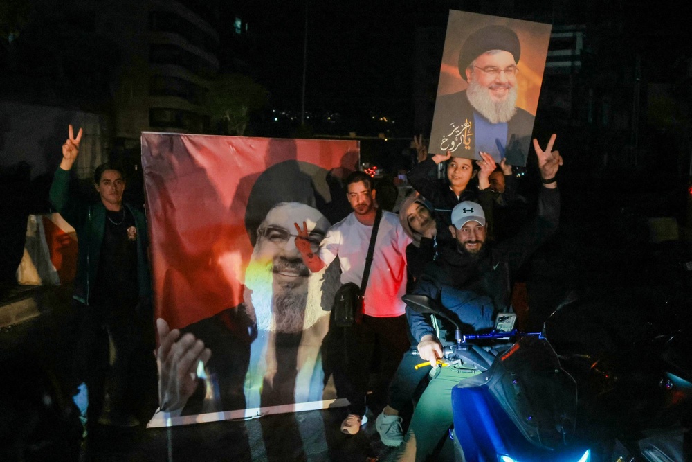 Hezbollah supporters hold photos of assassinated leader Hassan Nasrallah while celebrating the ceasefire (AFP via Getty Images)