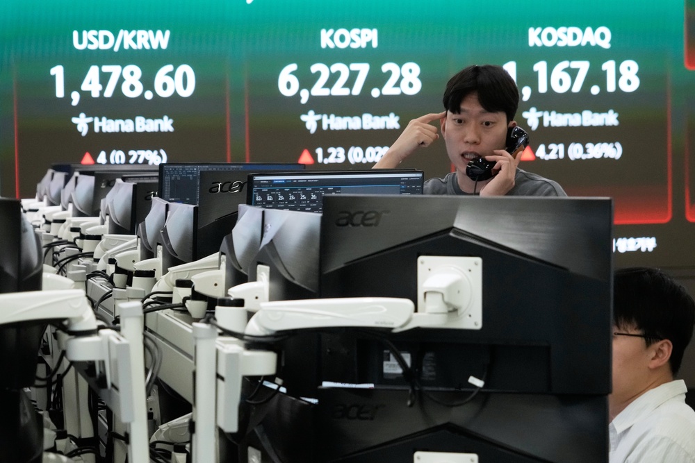 A currency trader talks on the phone near a screen showing the Korea Composite Stock Price Index (KOSPI) (AP)