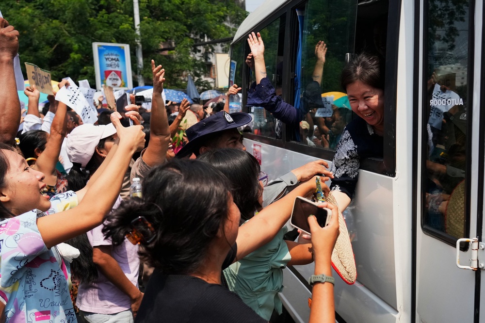 Released prisoners, in a bus, are welcomed by family members and colleagues after they left Insein Prison in Yangon, Myanmar (AP)