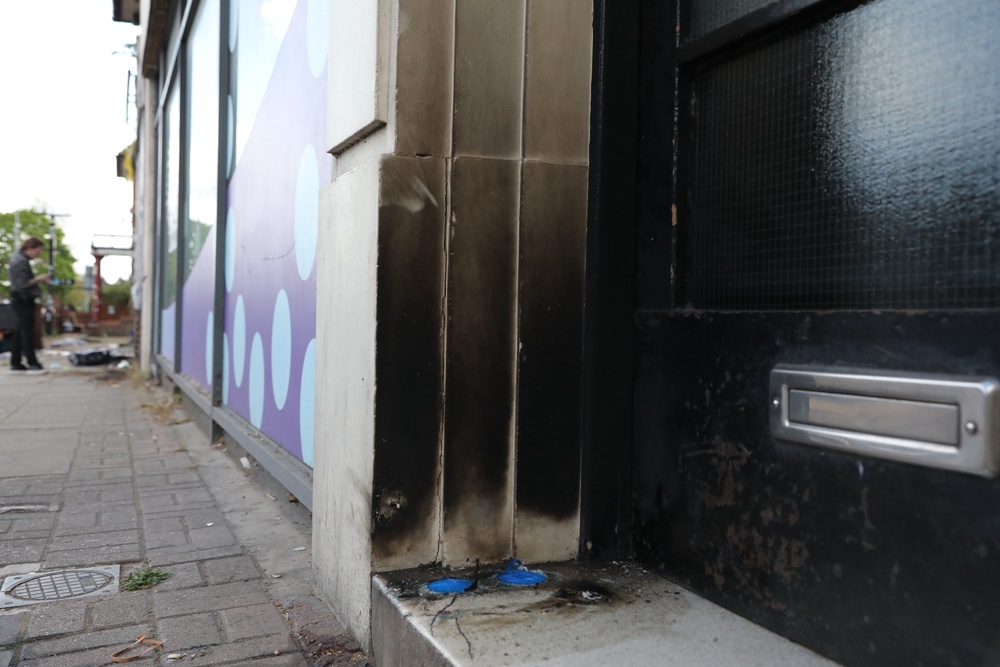 A close-up of some damage to a doorway by a row of shops as police investigate the scene of an attempted arson attack (Getty Images)
