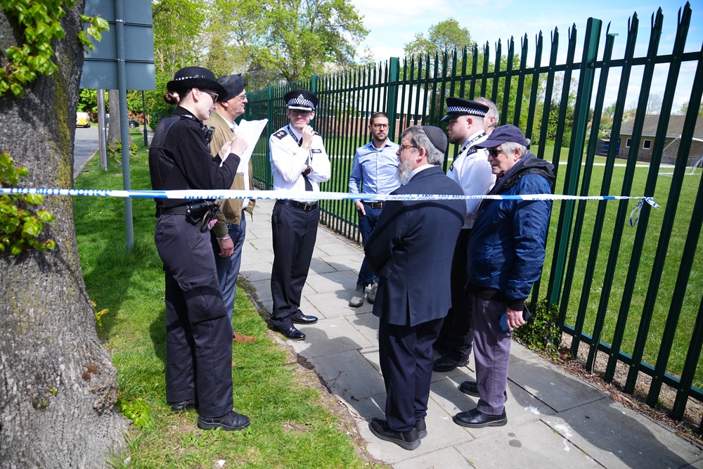 Rabbi Yehuda Black (centre) identifies himself to a police officer as he enters the restricted zone outside the synagogue (James Manning/PA) (PA Wire)