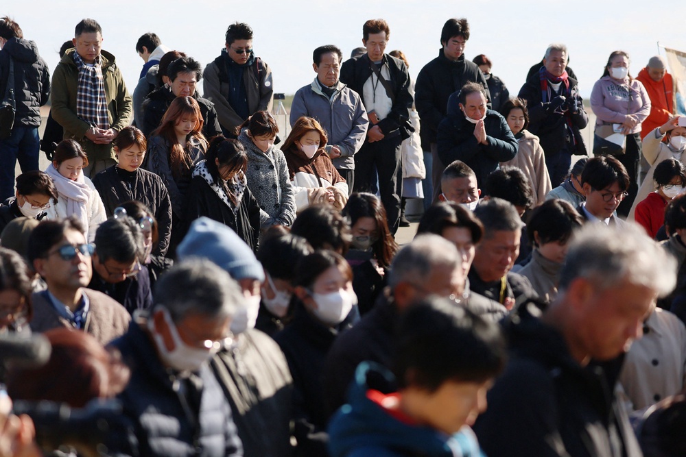 People pray silently at the time of the Great East Japan earthquake, 2.46pm in Natori City, Miyagi prefecture on the 15th anniversary of the 2011 earthquake and tsunami disaster (AFP/Getty)