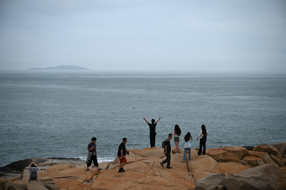 People look out to the Taiwan strait at a tourist spot called