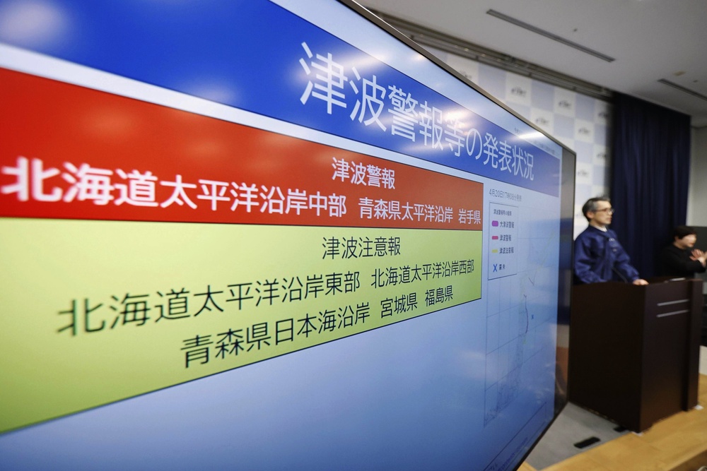 An official of the Japan Meteorological Agency speaks near a monitor showing a tsunami alert during a news conference at the agency in Tokyo (Kyodo News)