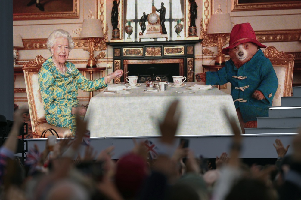 Crowds watch a film of Queen Elizabeth II having tea with Paddington Bear on a big screen during the Platinum Party at the Palace (PA)