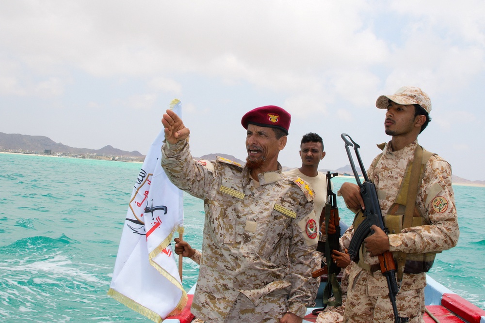 A Yemeni government army officer gestures from a boat in Bab el-Mandeb (Reuters)