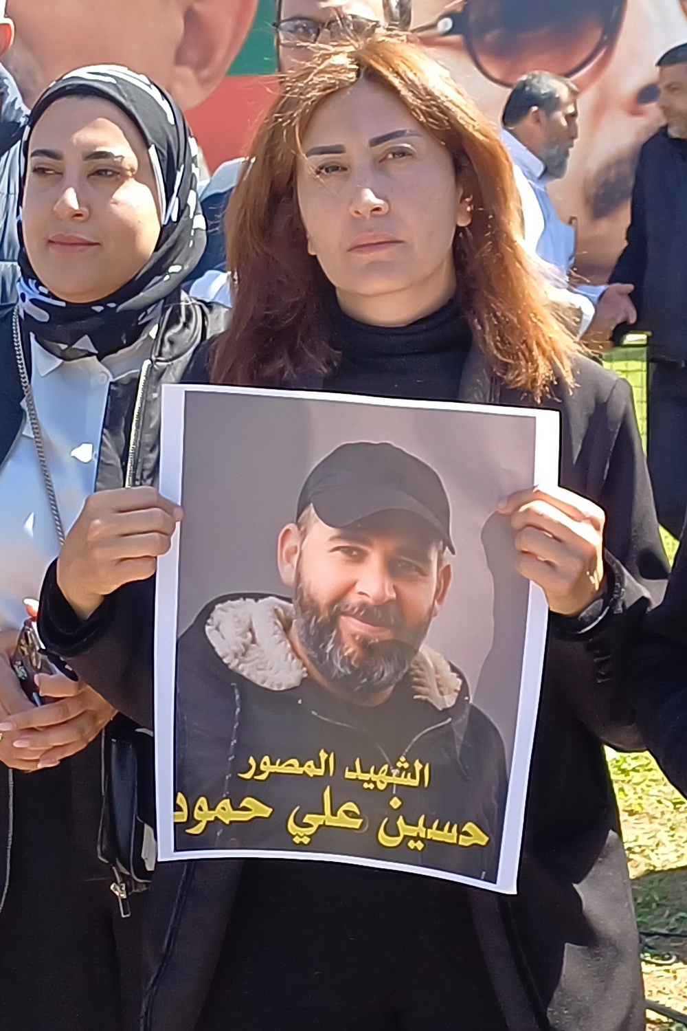 Lebanese journalist Amal Khalil holds a portrait of a photographer who was killed in an Israeli airstrike during a sit-in in the southern port city of Sidon. (AP)