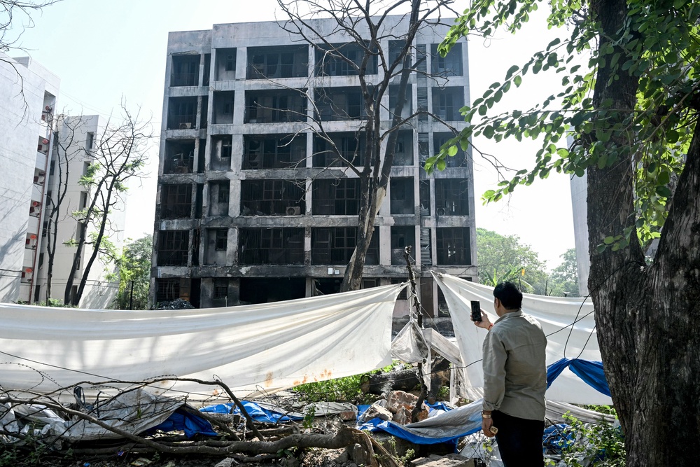 A man takes pictures of a charred building at the site of Air India flight AI171’s crash (AFP/Getty)