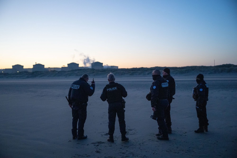 French police officers talk on a radio as they hear that a group of migrants are approaching the beach (Getty)