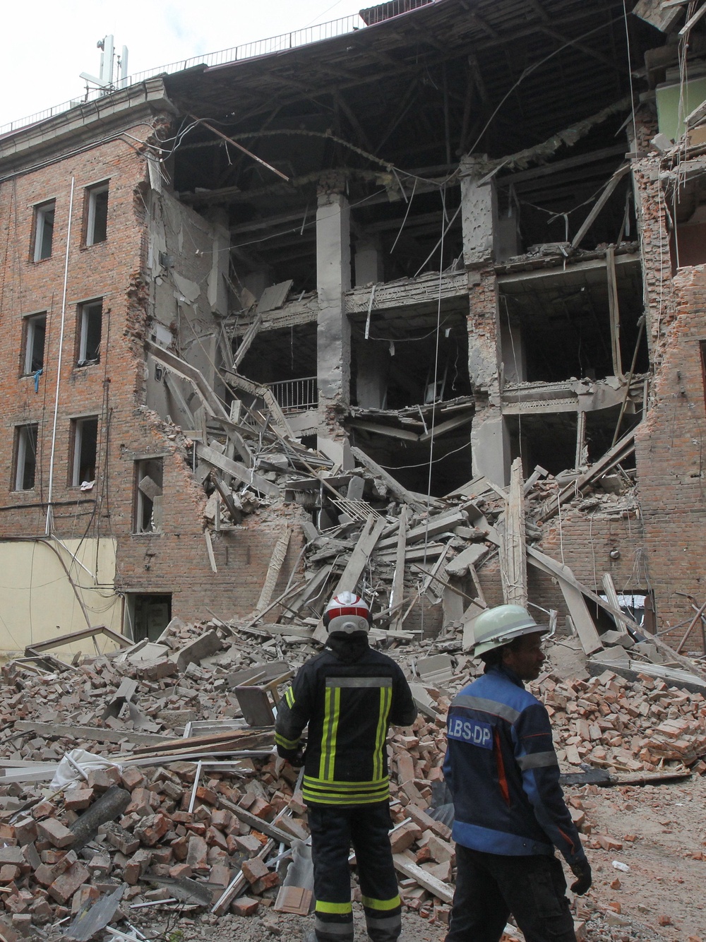 Rescuers stand in front of a residential building hit during a midday Russian drone strike (Reuters)