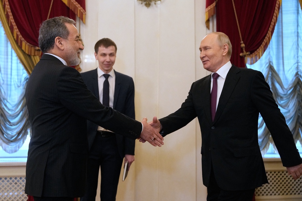 Vladimir Putin shakes hands with Iranian Foreign Minister Abbas Araghchi on Monday, in St Petersburg (AFP/Getty)