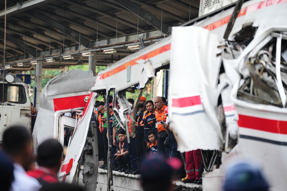 Workers and rescuers examine the wreckage following the collision (AP)