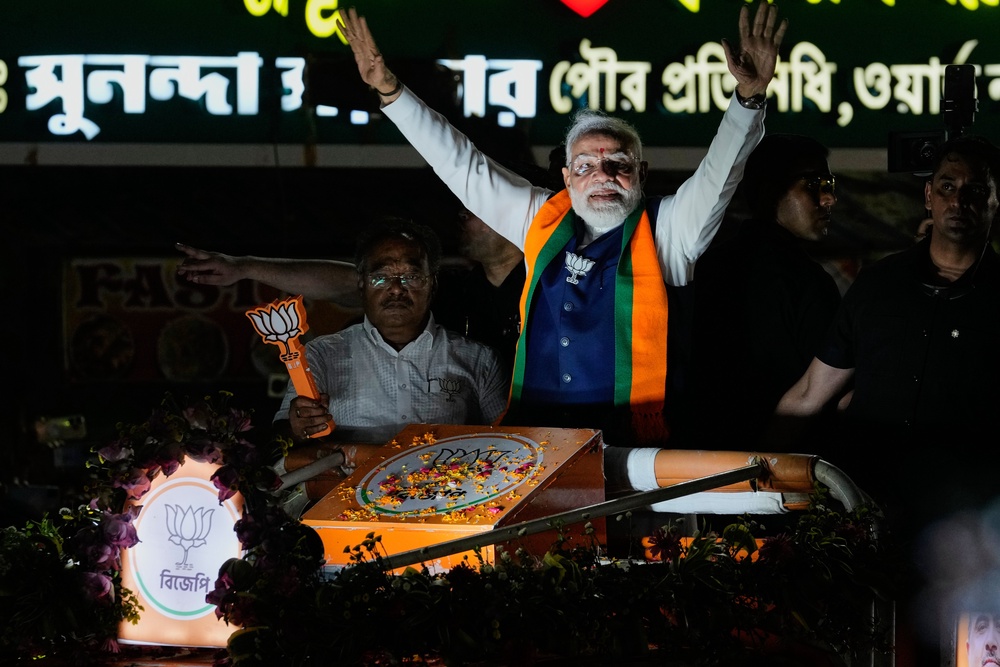 Narendra Modi waves to the crowd during a campaign roadshow for his party’s candidates in West Bengal (AP)