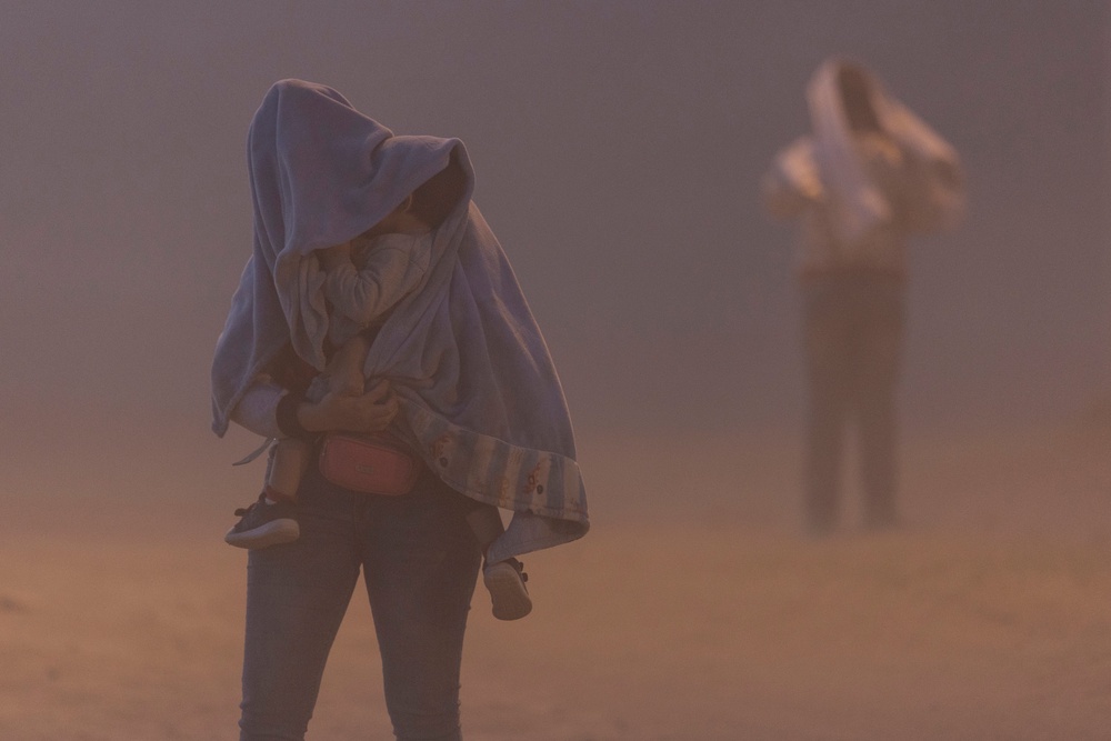 An immigrant mother and child from Venezuela walk through a dust storm while waiting to be processed for asylum claims in El Paso, Texas, in May 2023. Dust storms can cause reduced visibility (Getty)