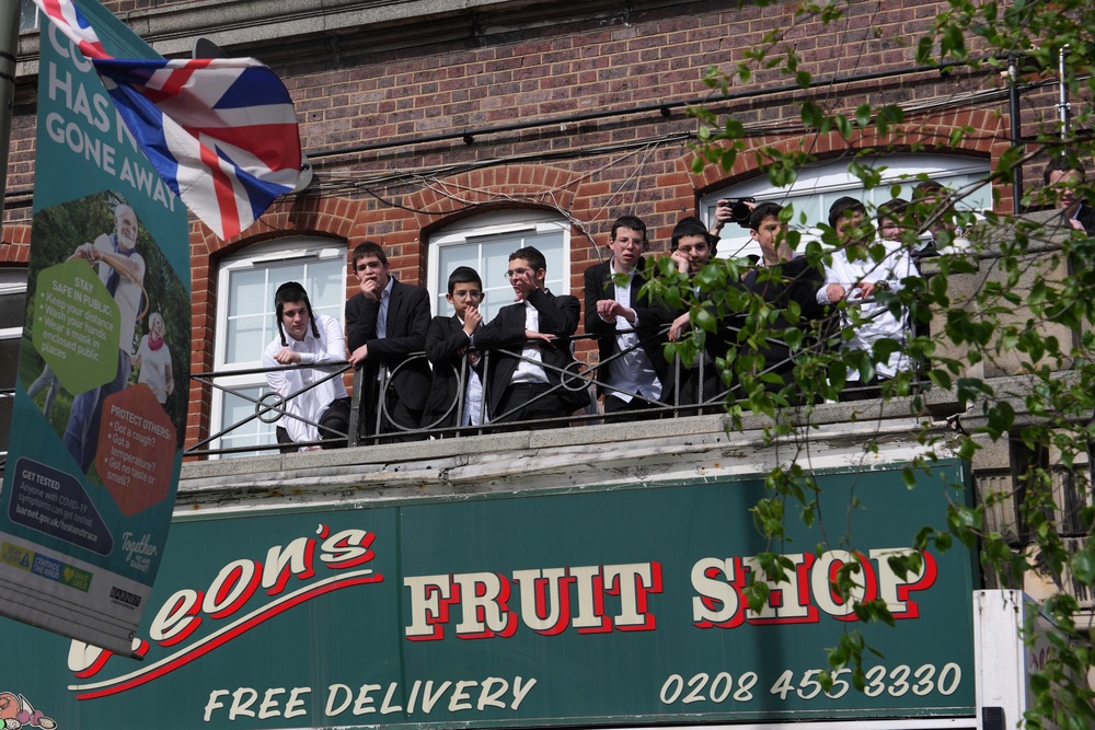 Members of the community watch on as police cordon off the street (AP)