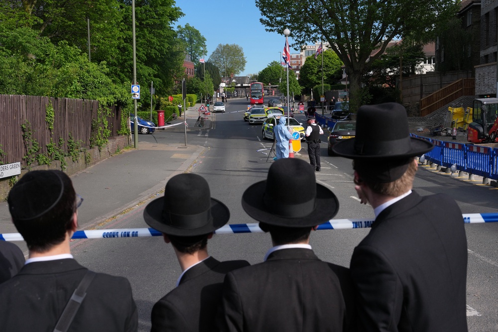 Members of the Jewish community watching police at the crime scene (AP)