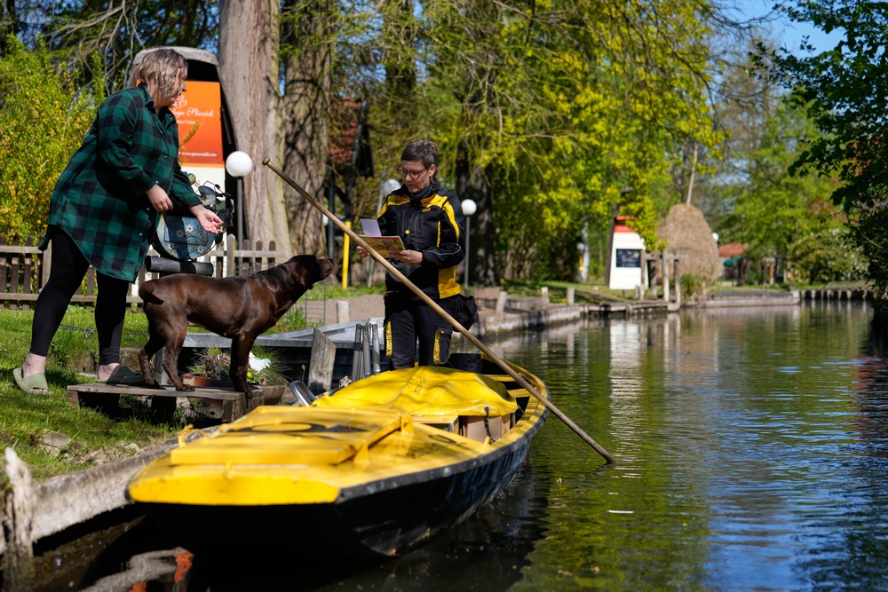 Mailwoman Andrea Bunar delivers mail from a boat during the first tour of the summer when mail delivered on the waterways in the village Lehde in Luebbenau, Germany (AP)
