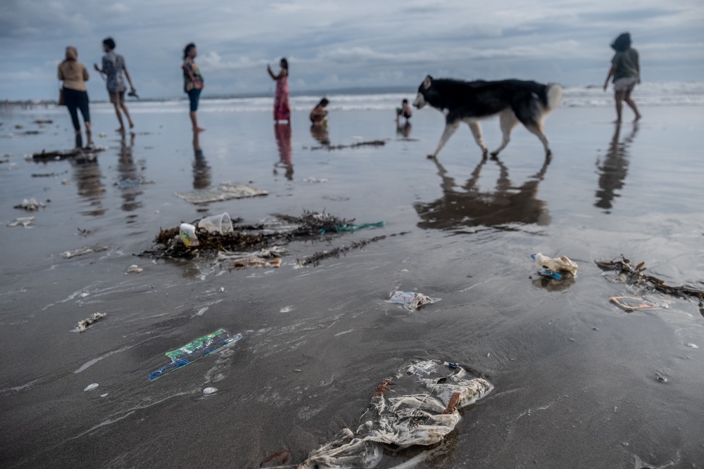 Trash is seen scattered at the Seminyak beach while tourists enjoy the sunset (Getty)