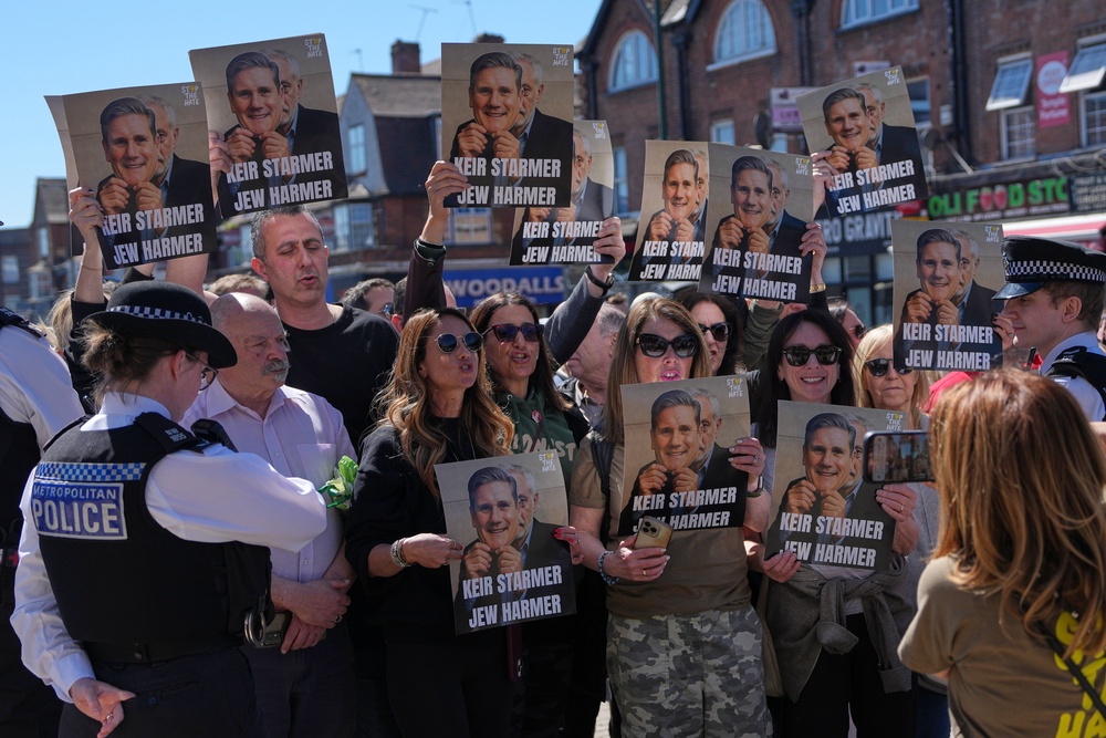 Protesters hold posters near the scene where two people were stabbed yesterday (AP)