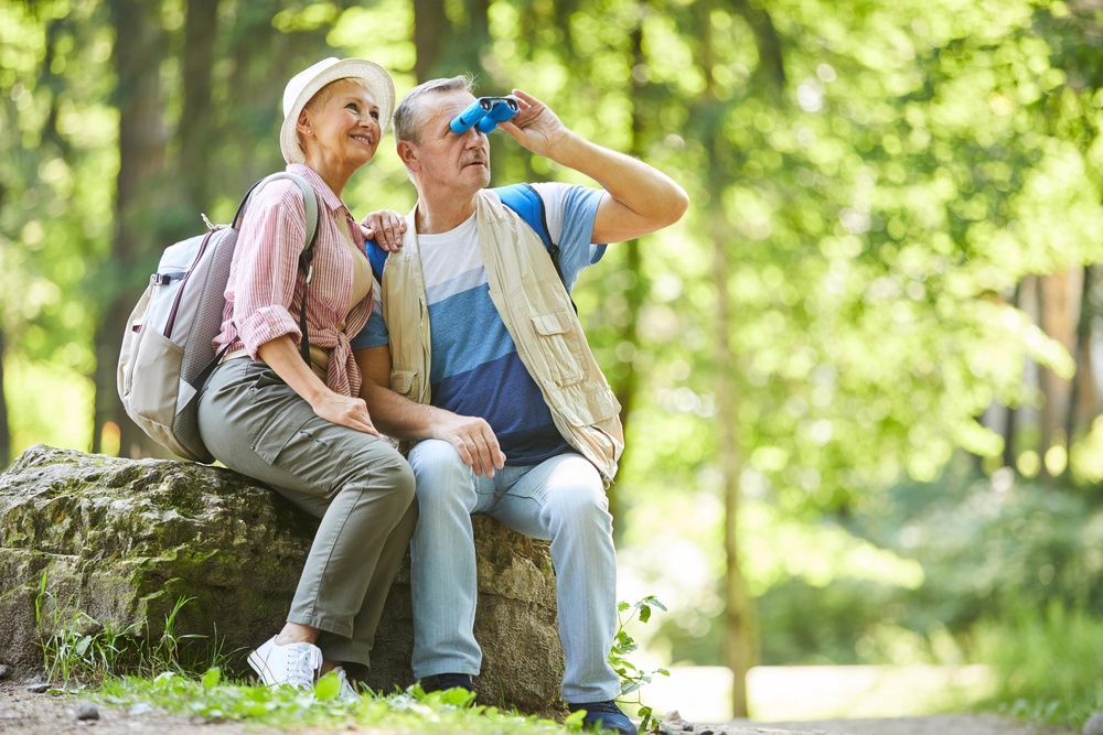 Senior couple sitting in a forest watching birds through binoculars (Alamy/PA)