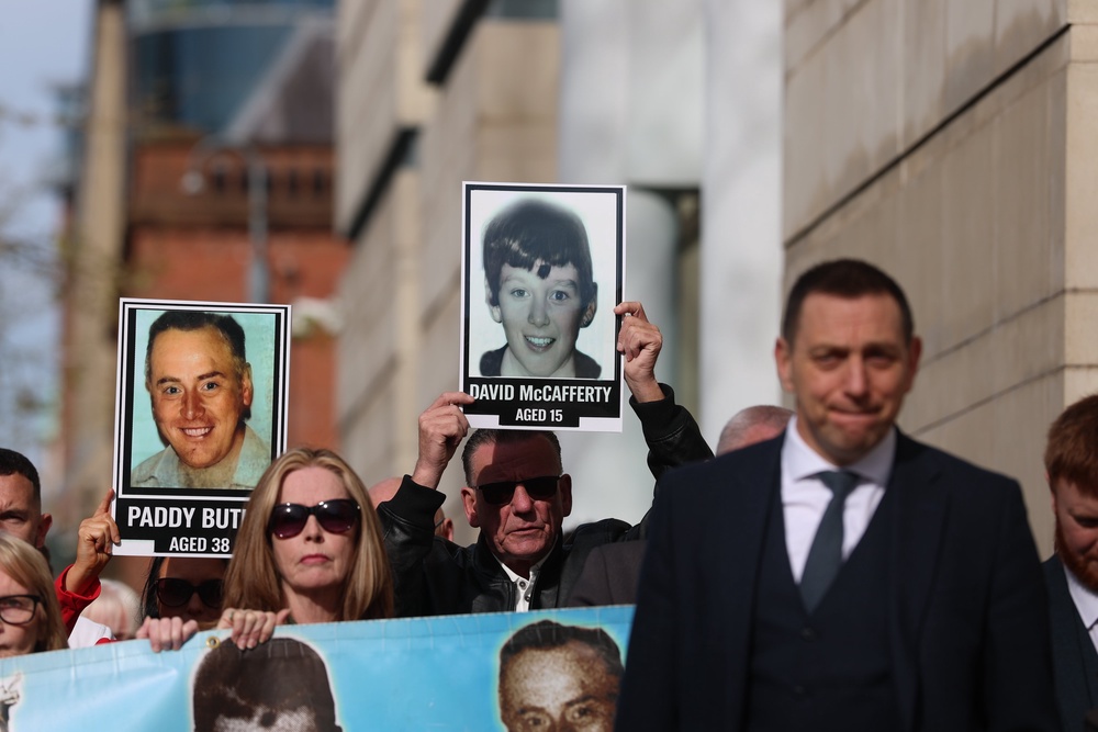 Relatives of those killed during the Springhill Westrock killings with their solicitor Padraig O Muirigh of O Muirigh Solicitors, holding a banner and pictures of the victims (Liam McBurney/PA) (PA Wire)