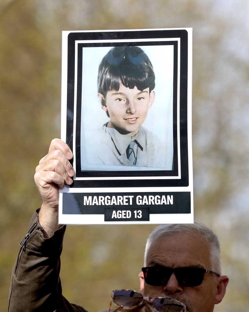 A Springhill Westrock campaigner holds an image of Margaret Gargan as they arrive at Belfast Coroner’s Court (Liam McBurney/PA) (PA Wire)