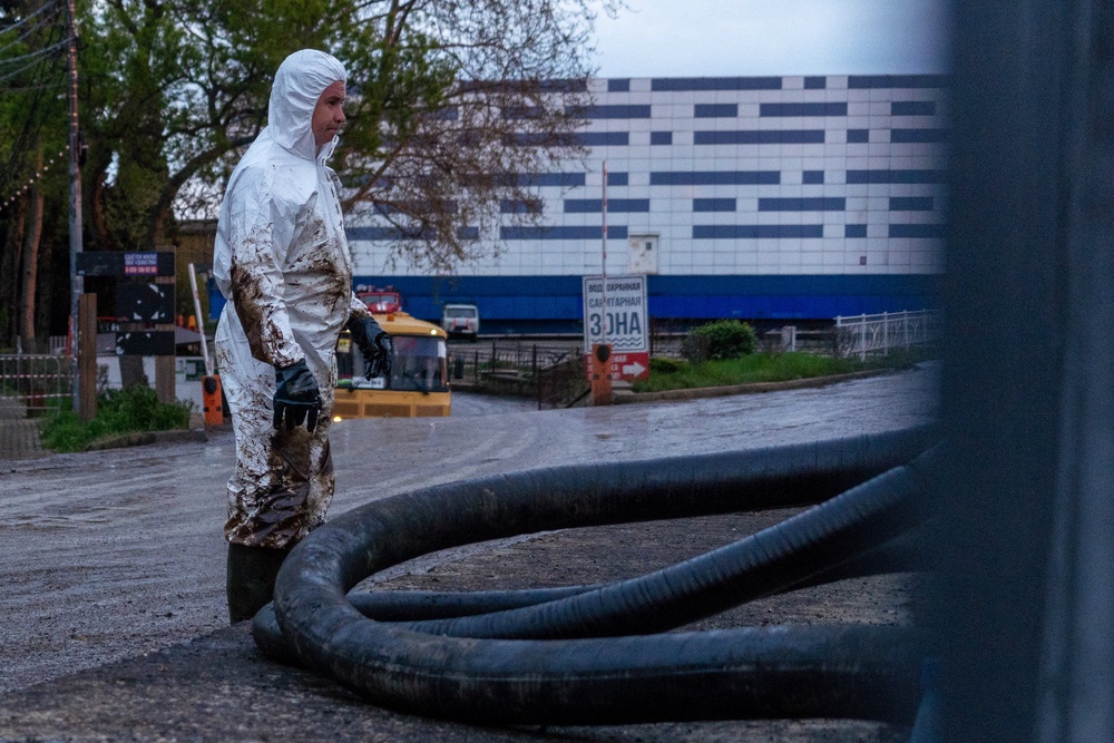 A worker stands next to a hose as he cleans the river of petroleum products following a spill caused by a recent drone attack on the Tuapse oil refinery in Tuapse, Krasnodar region (AFP/Getty)