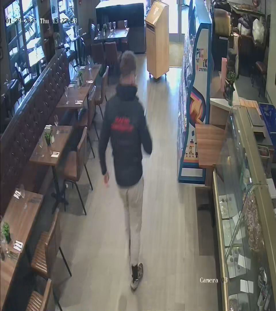 Suspect looks down at his mobile phone as he walks out of Relentless Steak and Lobster after allegedly not paying for their food (Scott Matthews)