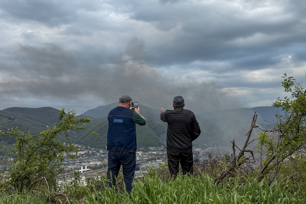 Local residents observe smoke rising above buildings following a recent drone attack on the Tuapse oil refinery in Tuapse, Krasnodar region (AFP/Getty)