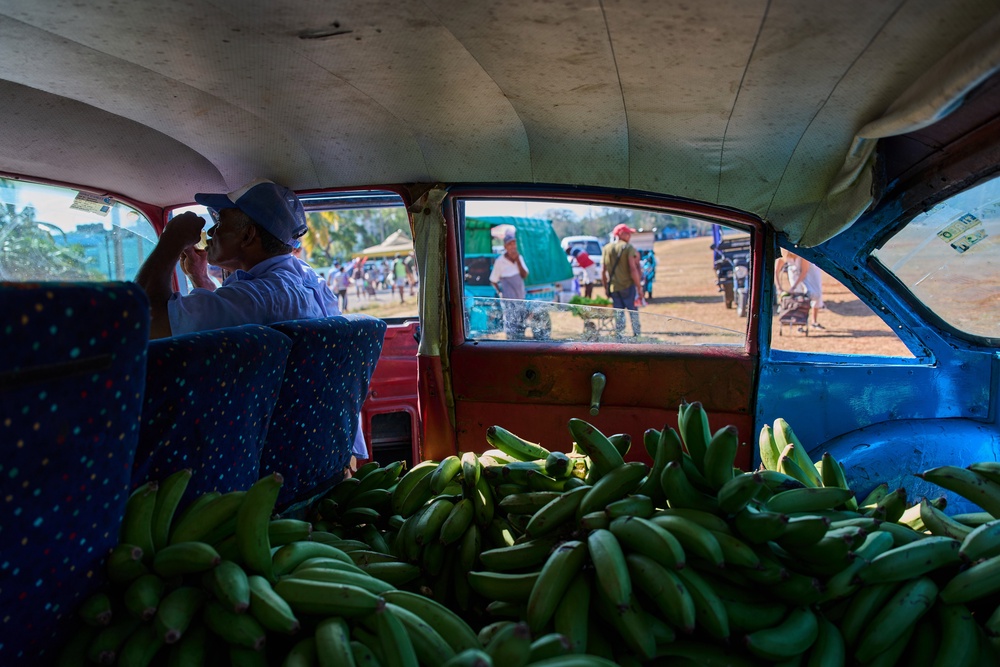 A vendor sits in the passenger seat of an American classic car, its back seat filled to the brim with bananas, while waiting for customers at a produce fair in Alamar, Havana province, Cuba, Saturday, May 2, 2026. (AP Photo/Ramon Espinosa) (AP)