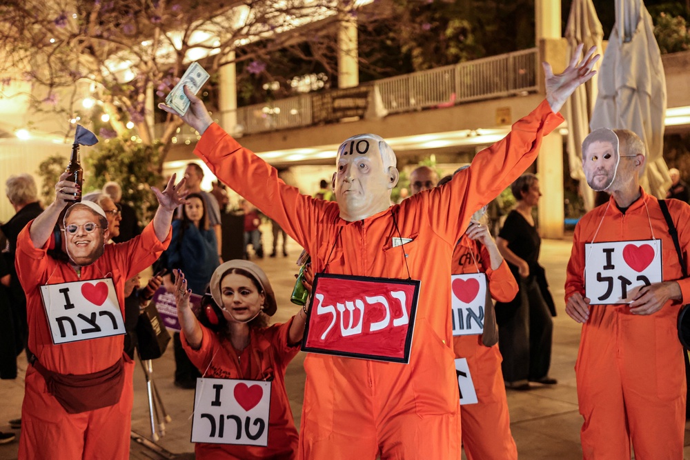 An Israeli left-wing activists wears a face mask depicting Israeli Prime Minister Benjamin Netanyahu and holding US dollars (AFP/Getty)