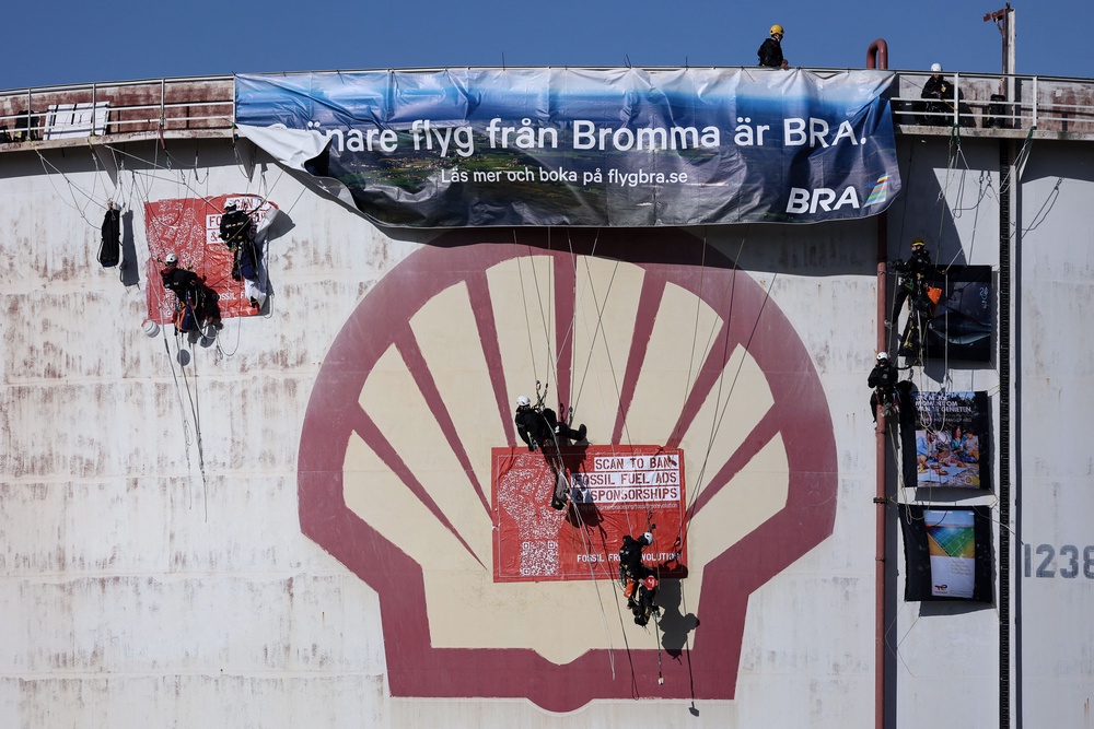 Activists of the environmental NGO Greenpeace climb a storage tank to hang a banner (AFP/Getty)