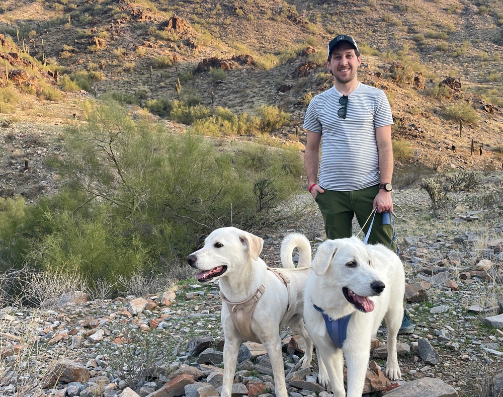 Noah Snyder-Mackler stands with his two dogs while out on a hike. Homer, a mix, appears on the left. Juno, a Great Pyrenees, looks to the right of the frame (Noah Snyder-Mackler)