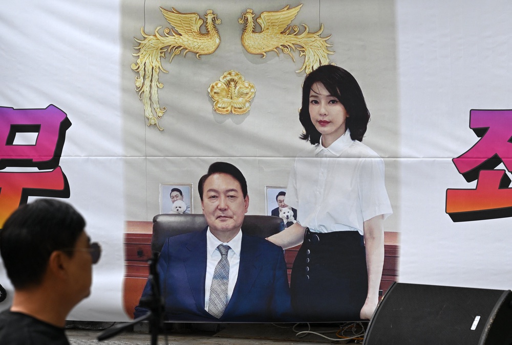 A man walks past a banner showing a picture of South Korea's former president Yoon Suk Yeol and his wife Kim Keon Hee on a street near the Seoul High Court in Seoul on April 28, 2026 (AFP/Getty)