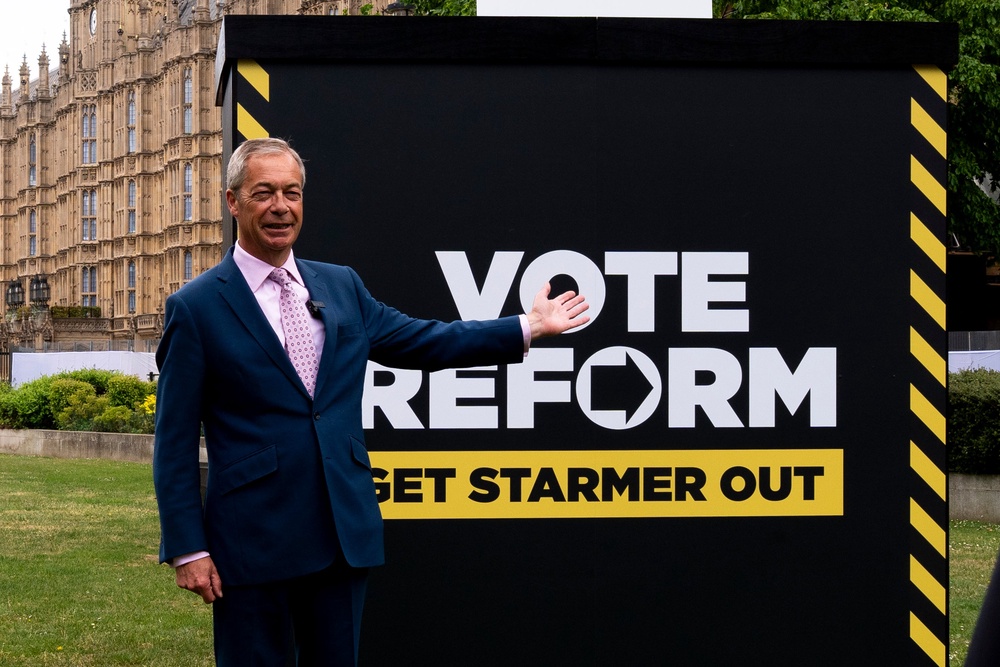 Nigel Farage in front of a sign reading 'Vote Reform, get Starmer out' in Westminster (PA)